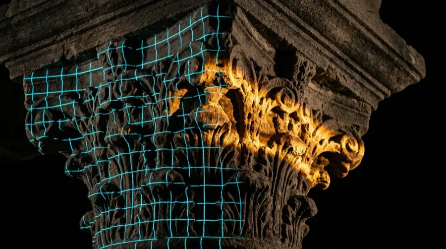 Un capitello in pietra attraversato da una griglia di luce ciano e da una fascia ambra.